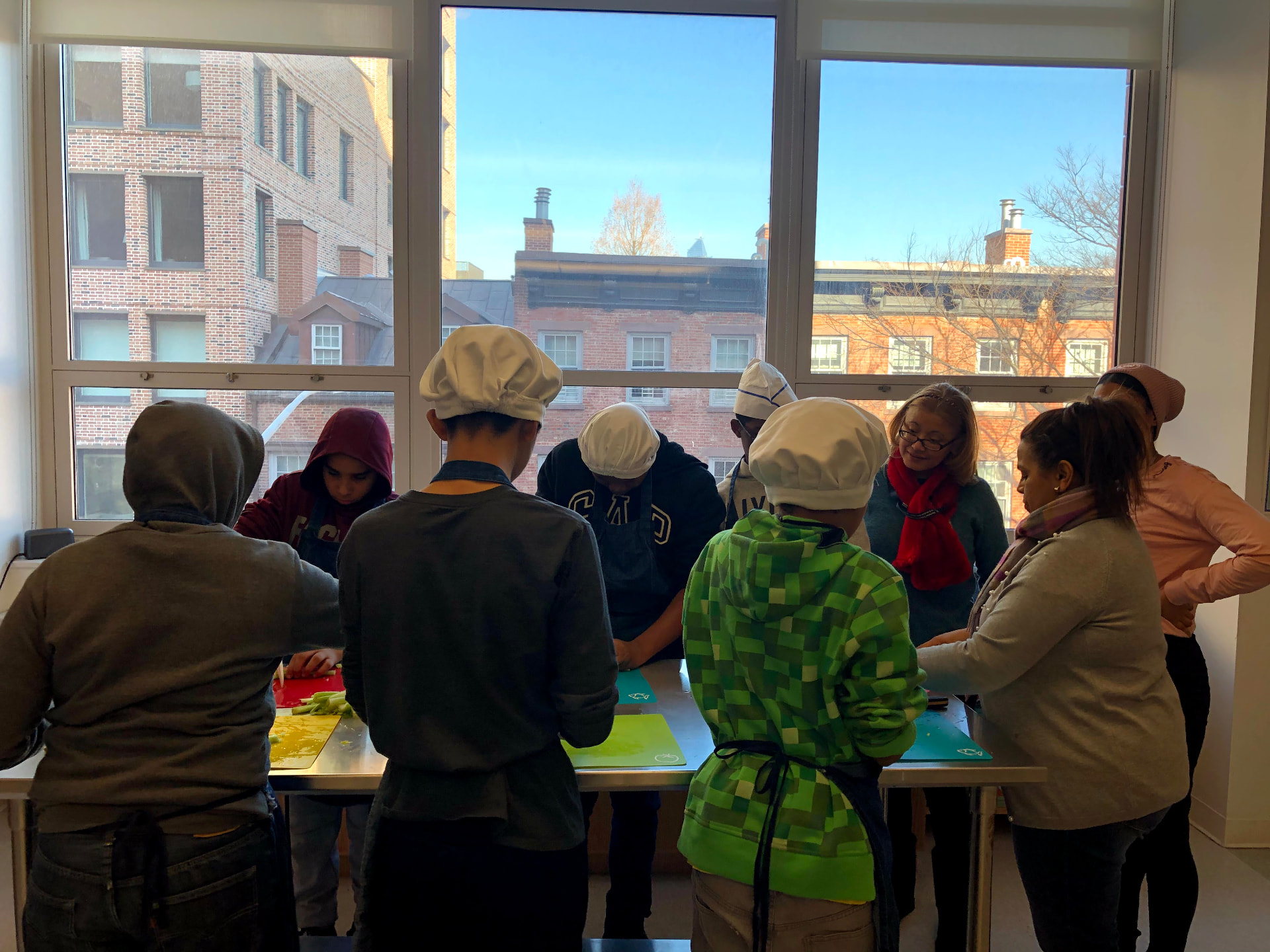 Chef Jeremy teaching a group of students prepping vegetables in a bright classroom kitchen